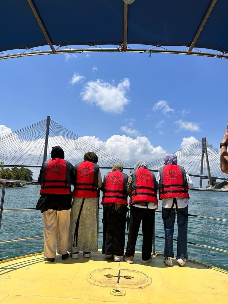 Guests in life jackets at the bow of a cruise boat, looking towards Barelang Bridge