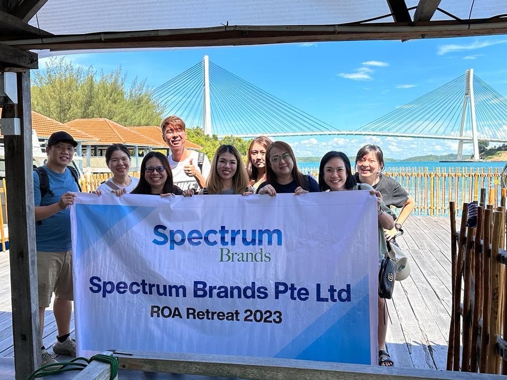 The Spectrum Brands team with their retreat banner on a jetty near Barelang Bridge