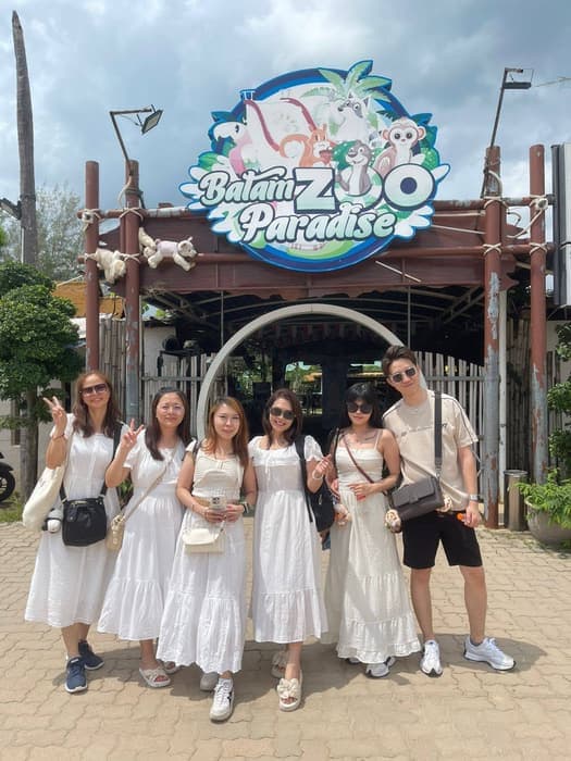 Six travellers dressed in white at the entrance arch to Batam Zoo Paradise.