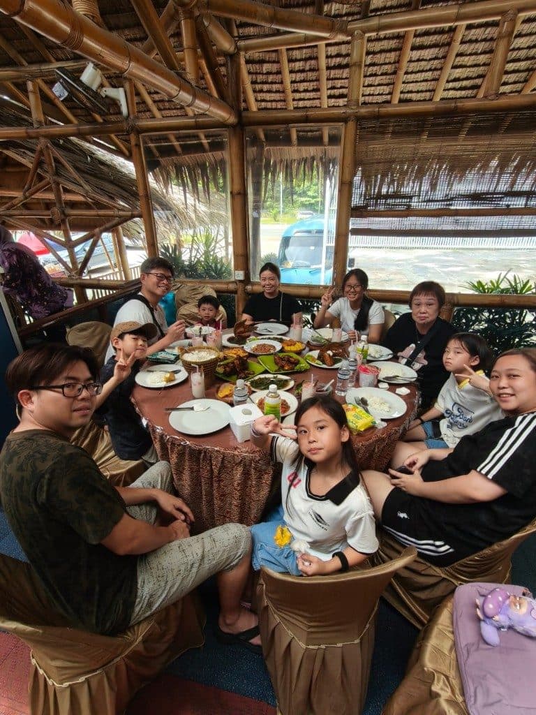 A family around a table of local dishes in a bamboo restaurant in Batam