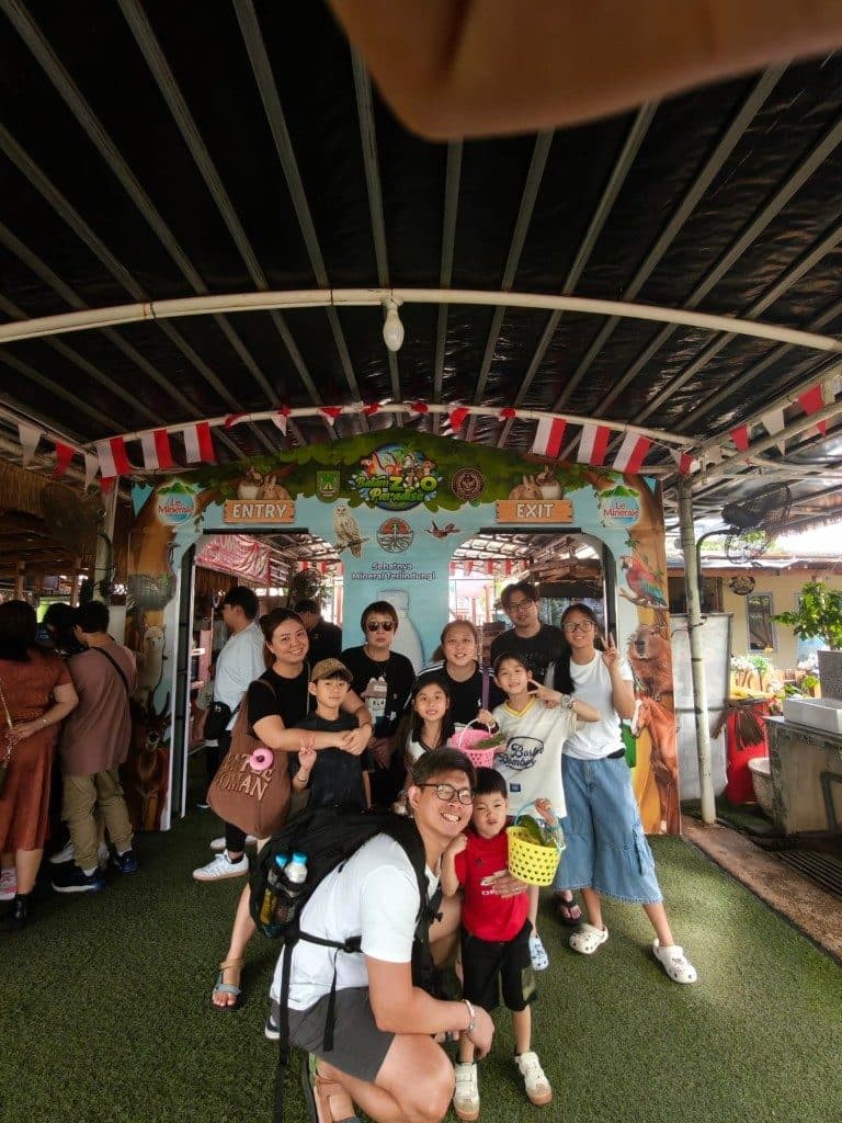 A family group under the Batam Zoo Paradise entry arch