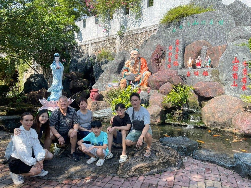 Guests beside the koi pond and stone statues of a Chinese temple garden in Batam