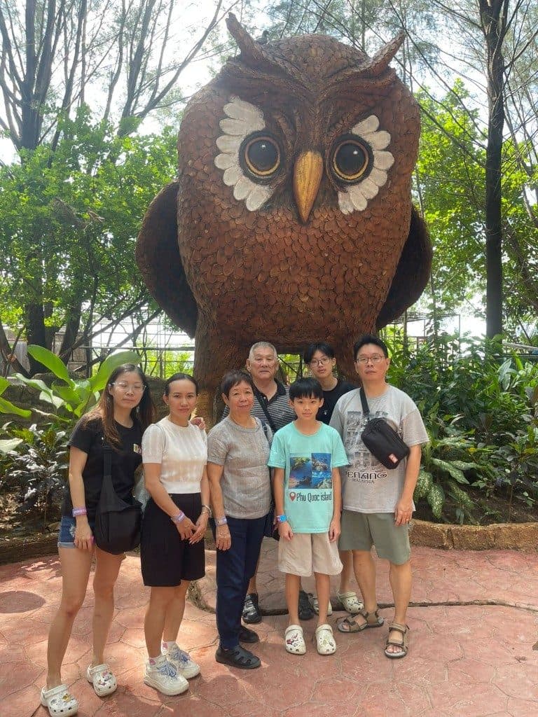 A family beside the giant woven owl sculpture at Dino's Gate